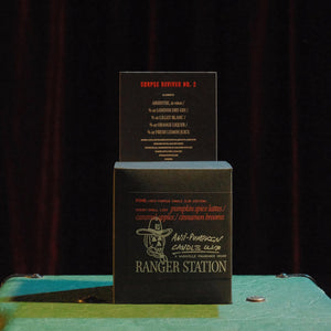 Two black boxes with text and branding on a green surface against a dark background